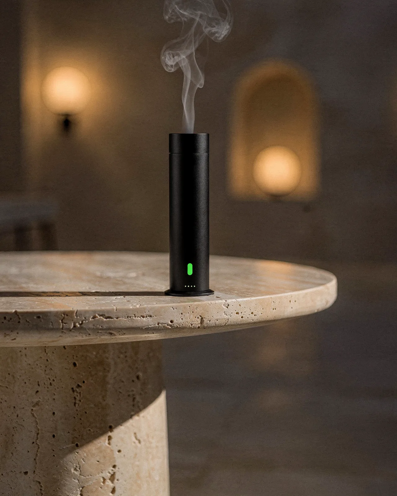 Black diffuser on a round travertine table, mist visible